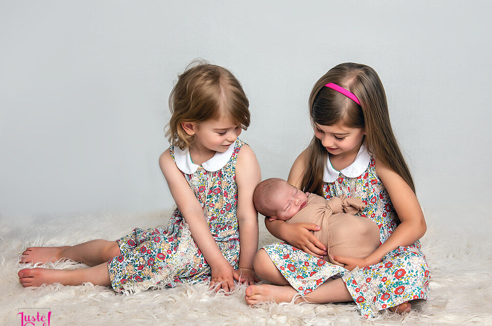 bébé nouveau-né photographié avec ses soeurs